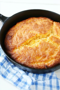 Freshly baked spoon bread with a light, fluffy interior, presented on a wooden table for a homestyle feel.