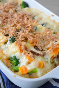 Freshly baked vegetable casserole with a crunchy layer on top, styled on a dark blue cloth.