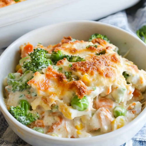 Hearty casserole showcasing vibrant vegetables coated in creamy sauce, finished with a crisp garnish.