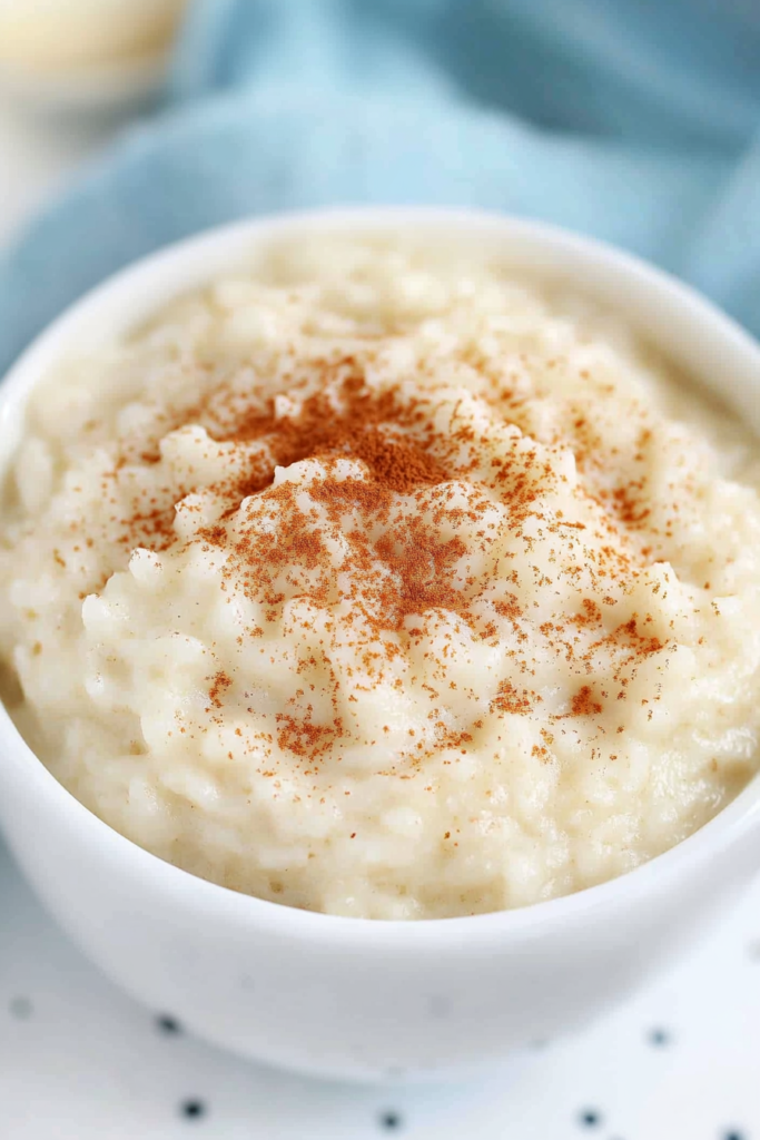 Close-up of thick, smooth pudding with visible grains of rice and warm spice dusting.
