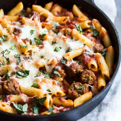 Cheesy pasta skillet loaded with sliced sausage, tomato sauce, and tender pasta tubes.