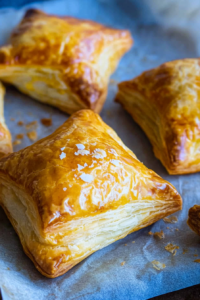Freshly baked savory puffs with a shiny golden top and buttery layers
