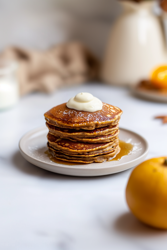 Stack of fluffy gingerbread pancakes topped with butter and warm maple syrup.