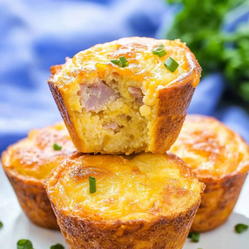 Bite taken from a warm egg muffin showing a tender interior with diced ham pieces