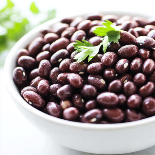 Cooked adzuki beans with a rich, dark sheen, presented simply in a bright kitchen setting.