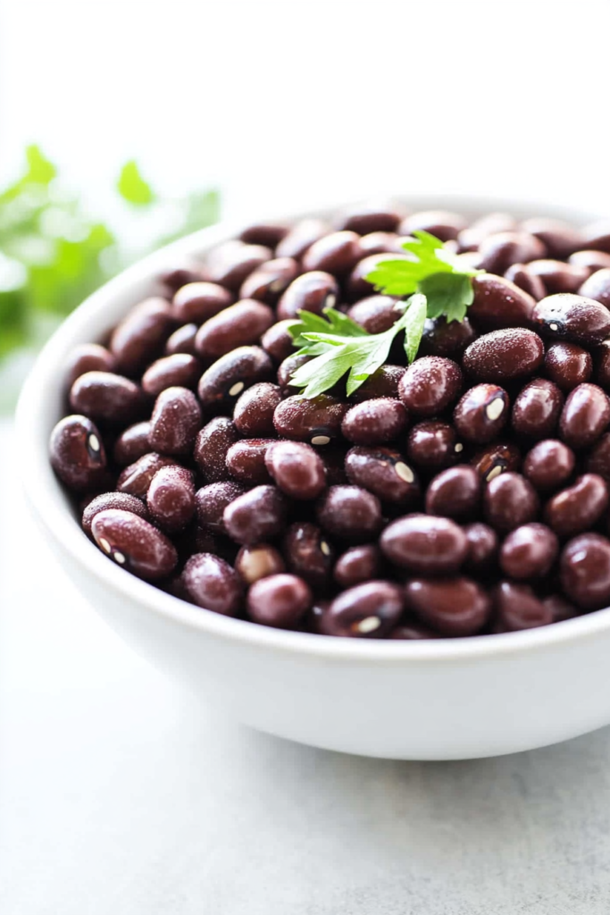 Cooked adzuki beans with a rich, dark sheen, presented simply in a bright kitchen setting.