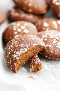 Round spiced holiday cookies lightly coated in powdered sugar, showing their soft and chewy crumb.