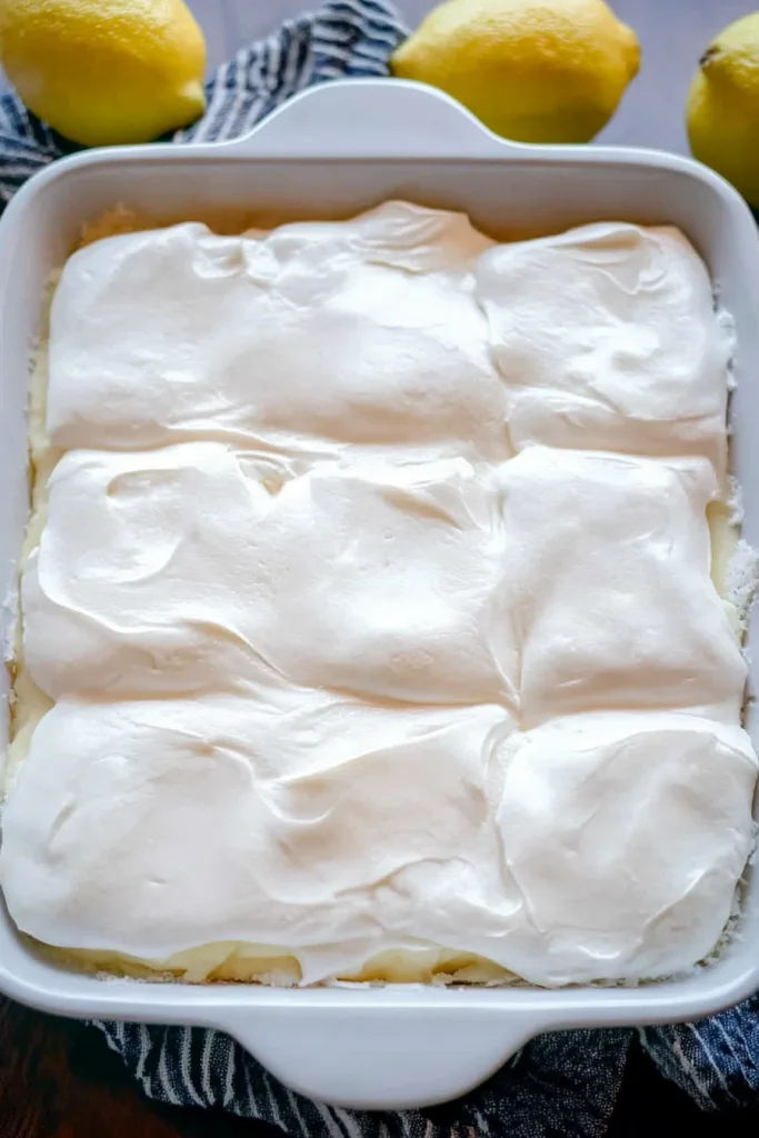 Light and fluffy lemon dessert bars topped with whipped cream and a buttery base.