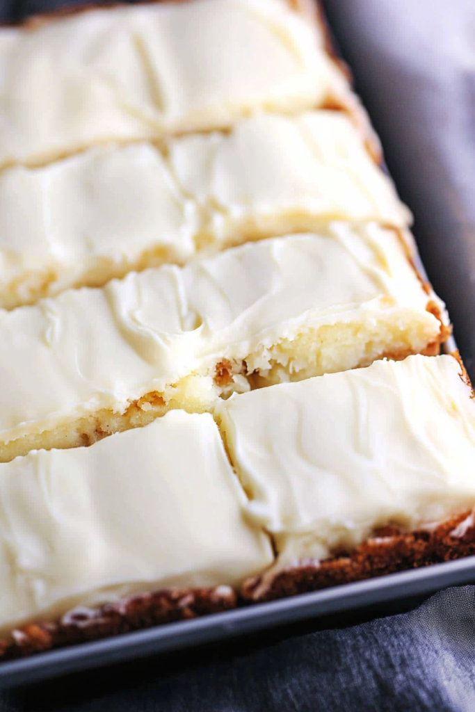 Tender butter cake with creamy topping and chopped nuts, served as a finished dessert.