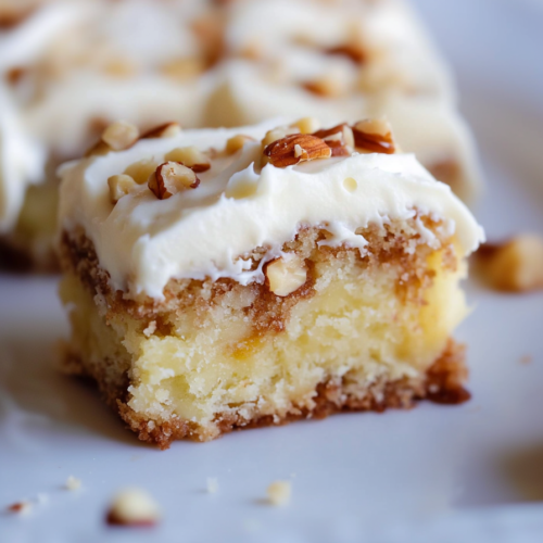 Frosted party cake slice with a soft crumb and pecan garnish, ready to serve.