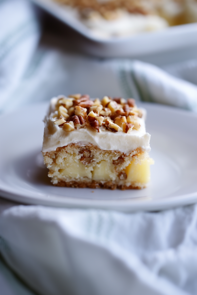 Slice of Mexican wedding cake topped with creamy white frosting and chopped pecans.