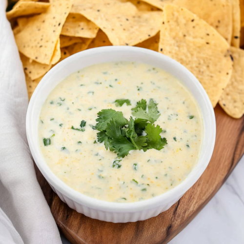 Bowl of rich, melted cheese garnished with cilantro leaves.