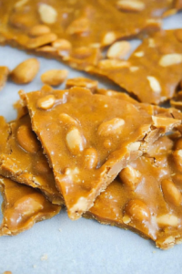 Broken pieces of nutty brittle arranged casually on a flat surface.