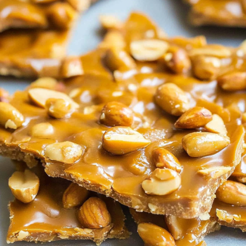 Peanut-studded brittle showing crisp edges and smooth, glossy finish.