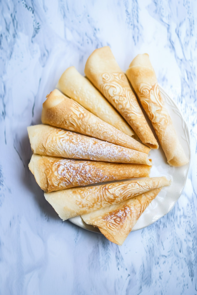 Thin, crisp cookies stacked neatly, showing their golden color and airy texture.
