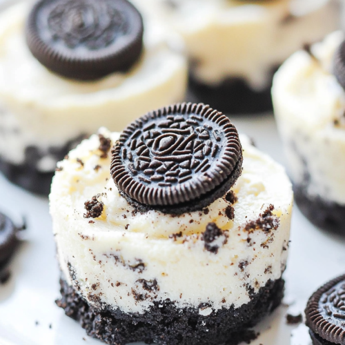 Close-up of bite-sized cheesecakes topped with whole Oreo cookies.