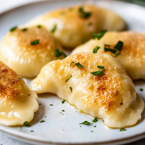 Plate of freshly cooked pierogi with crisp edges and soft dough.