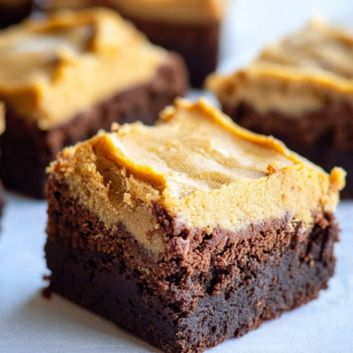 Close-up of fudgy brownies topped with a creamy pumpkin spice layer cut into squares.