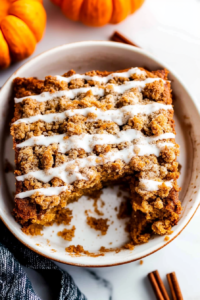 Warm fall-themed cake slice with streusel topping and decorative pumpkin nearby.