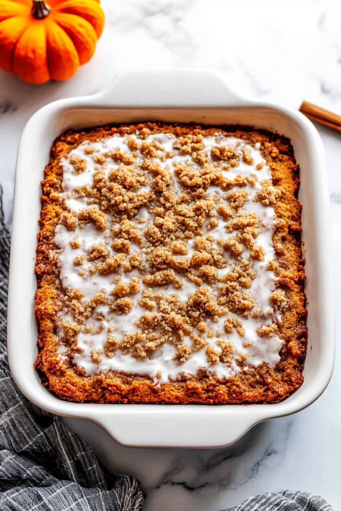 Dense, autumn-inspired cake served on a white plate, finished with sweet icing and crunchy topping.