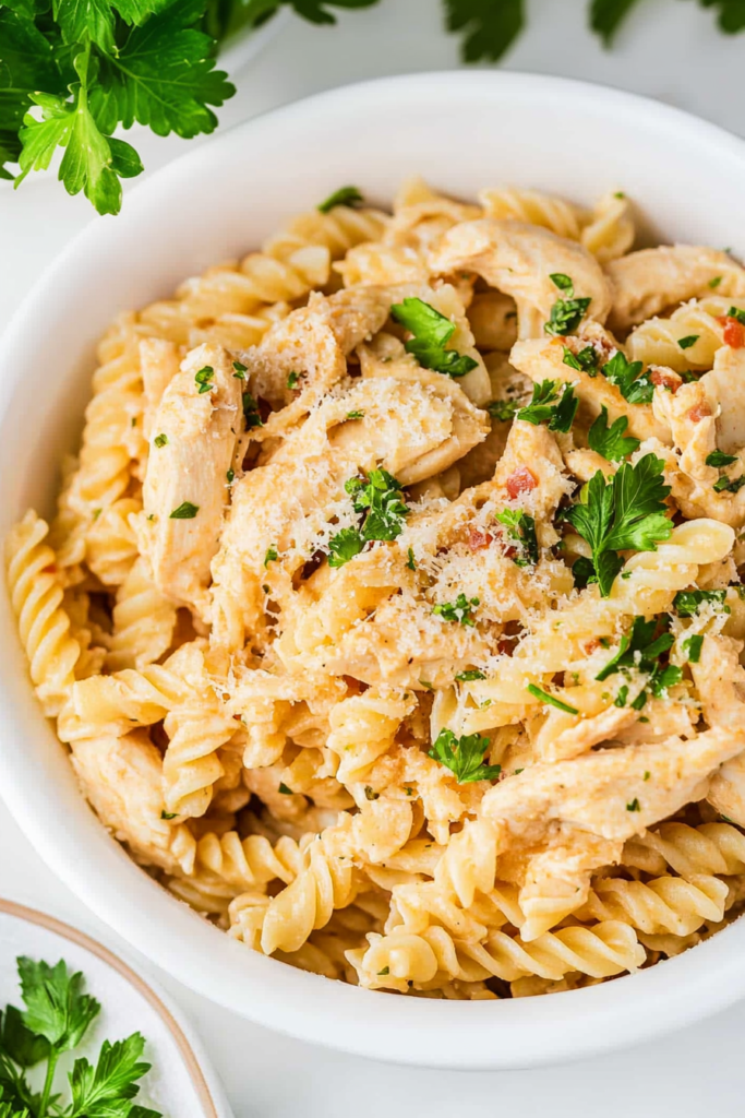 Close-up of tender chicken pieces mixed into spiral pasta with a rich, cheesy cream sauce.