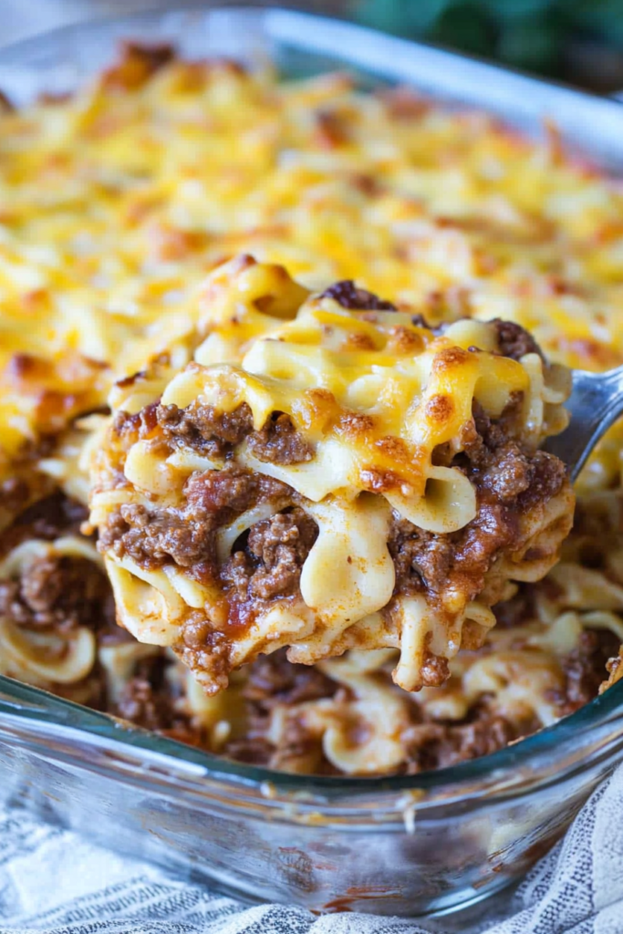 Close-up of wide egg noodles mixed with ground beef and tomato sauce, topped with melted cheese.