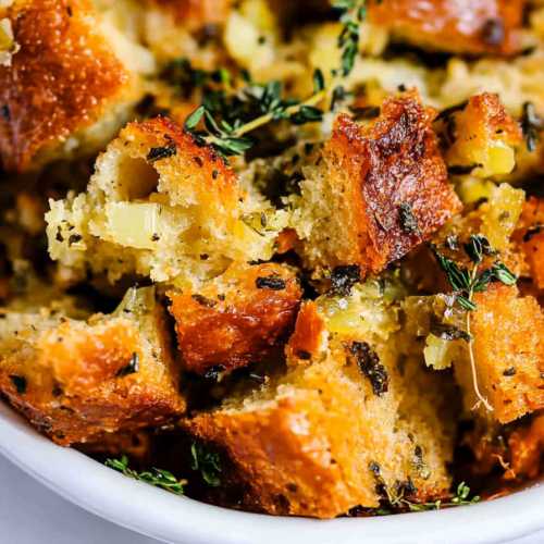 Final presentation of savory bread dressing with flecks of thyme and parsley.