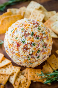 Creamy appetizer ball surrounded by assorted crackers on a wooden board