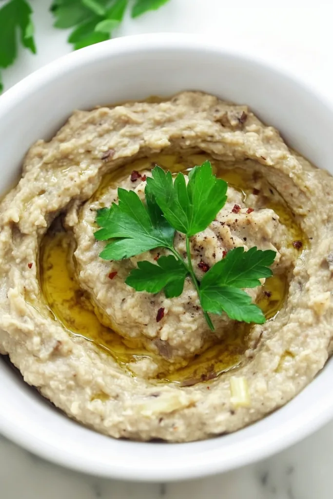 Smooth eggplant spread garnished with herbs and a drizzle of oil