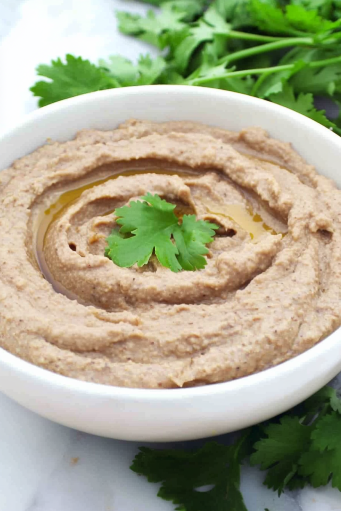 Close-up of a rich, blended bean spread with a swirl finish and green garnish
