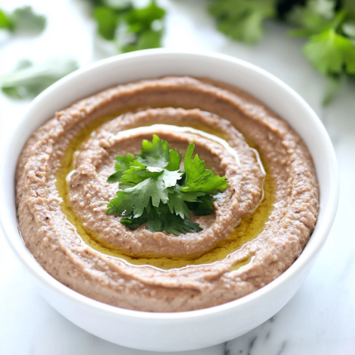 Smooth and savory bean dip garnished with a drizzle of oil and herbs