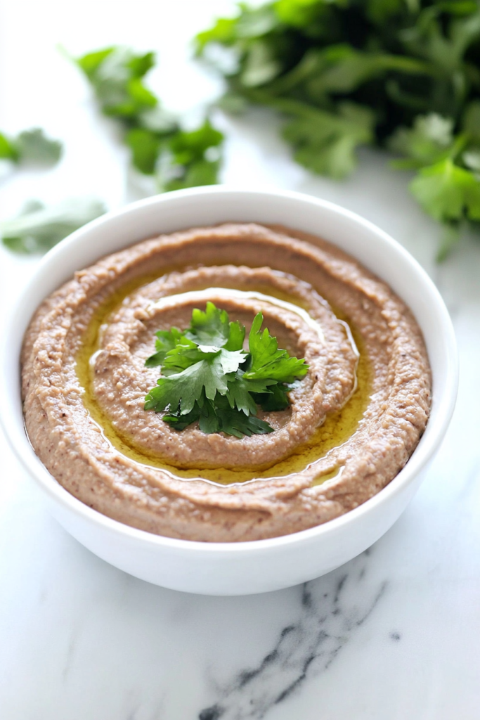 Smooth and savory bean dip garnished with a drizzle of oil and herbs