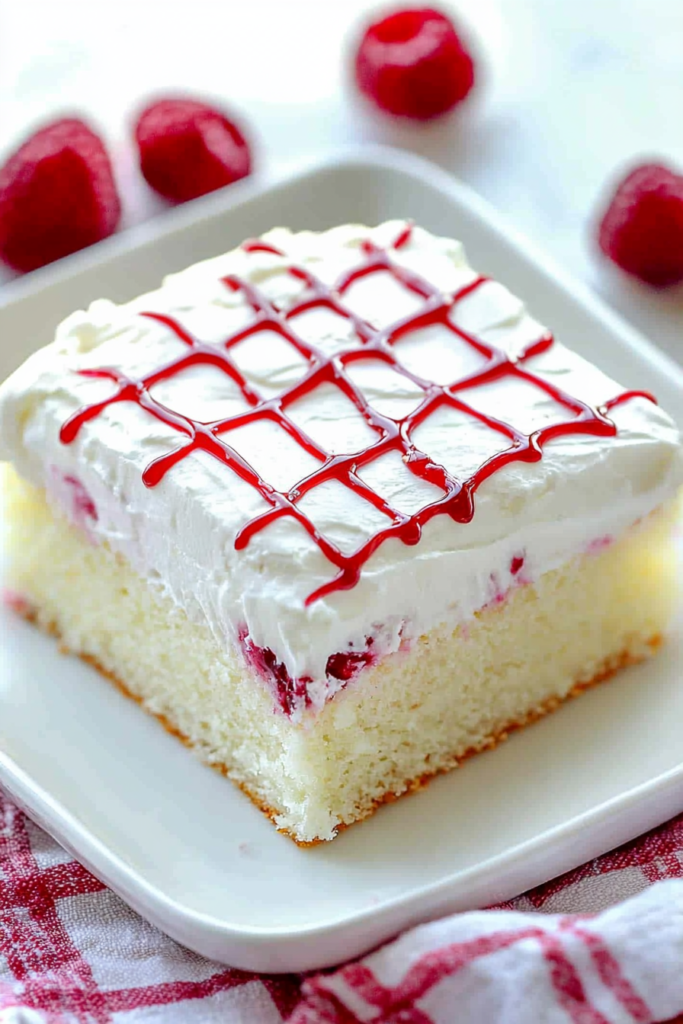 Overhead view of cake slice on a white plate, with fresh berries scattered in the background.