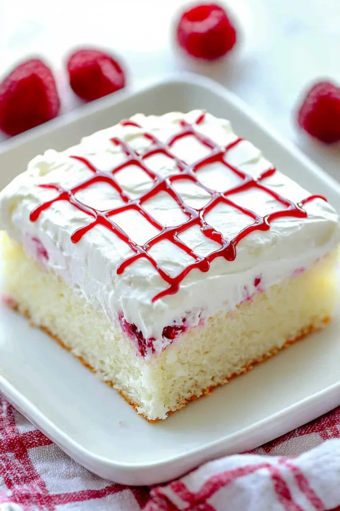 Overhead view of cake slice on a white plate, with fresh berries scattered in the background.