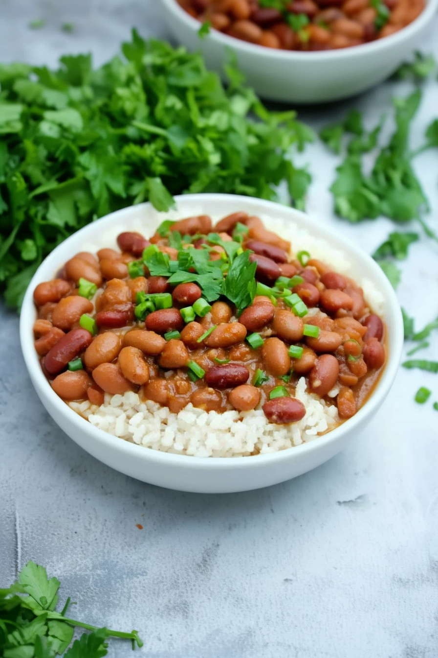 Bowl of red beans served over fluffy white rice with fresh herbs