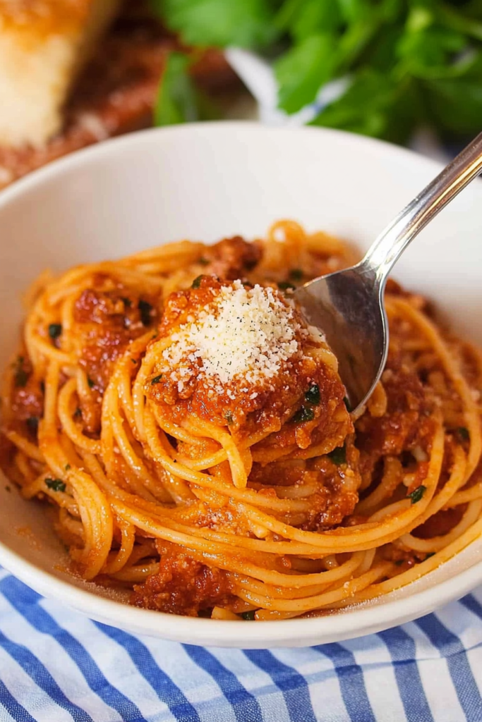 Final plated shot of Chicago Spaghetti, highlighting thick sauce, grated cheese, and fresh tomatoes