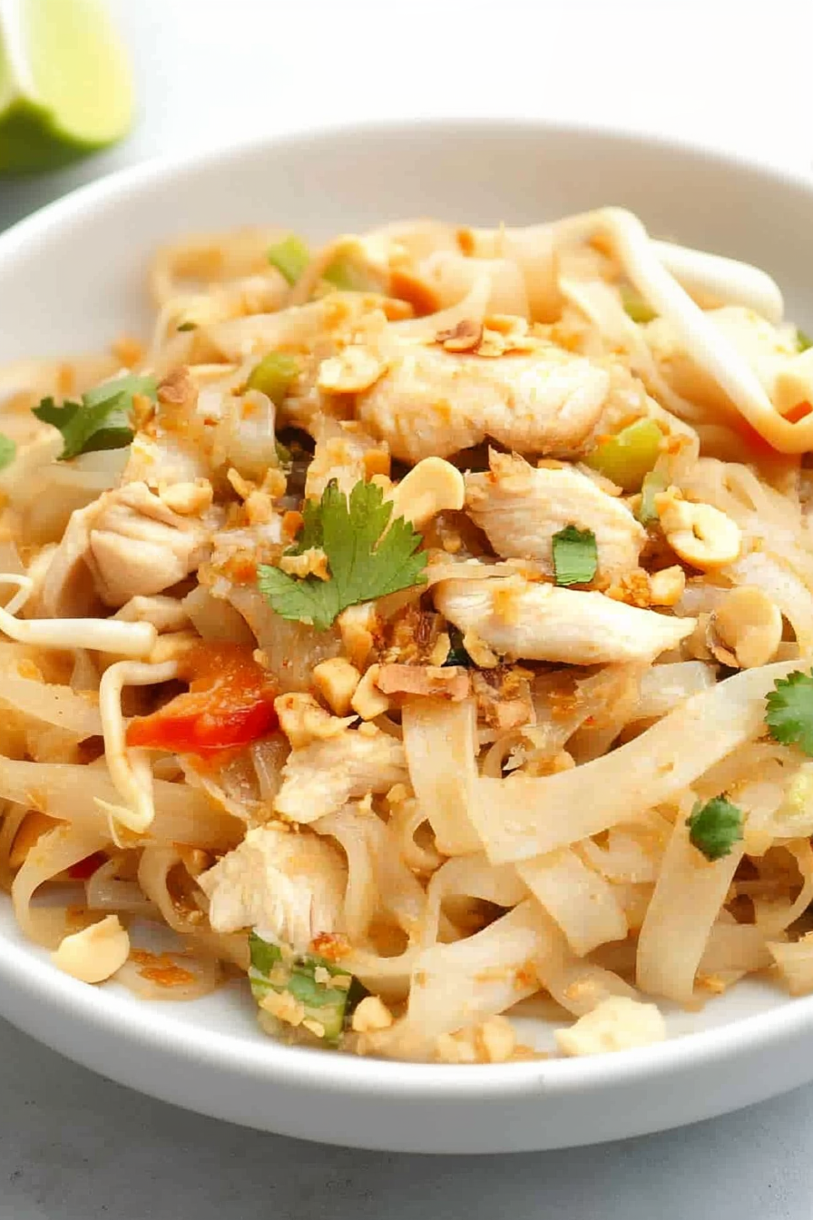 Appetizing noodle bowl highlighting tender chicken, sprouts, and bright garnishes.