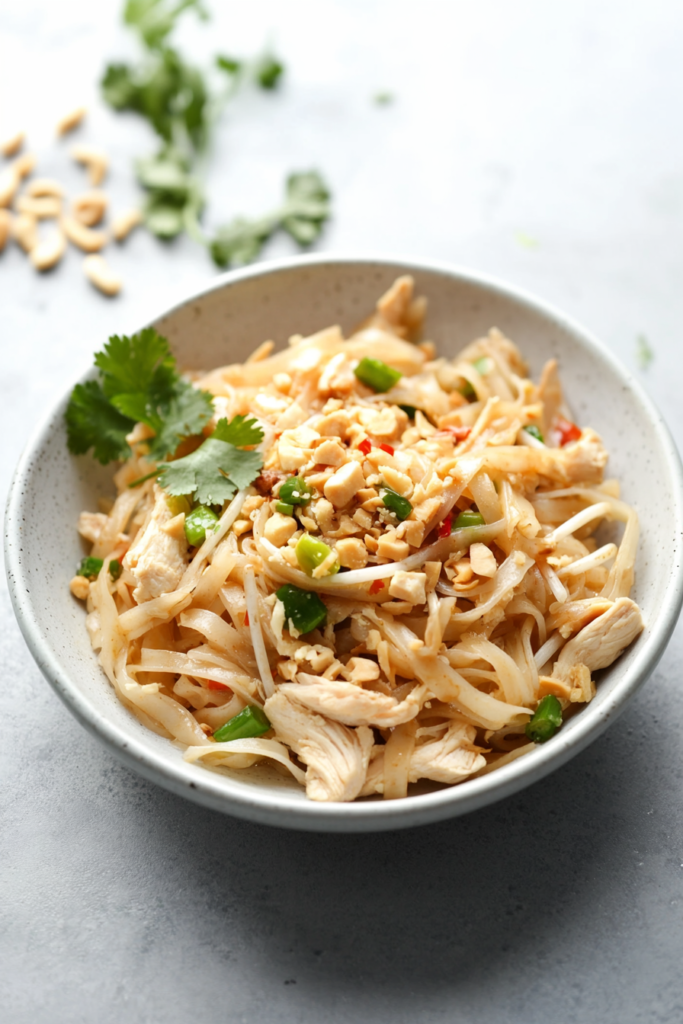 Colorful noodle dish topped with cilantro, bean sprouts, and crushed peanuts.