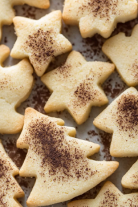 Golden star-shaped cookies dusted lightly with cocoa powder, arranged on a baking sheet.
