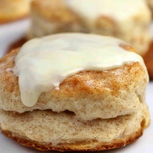 Rustic baked biscuit paired with another in the background, showcasing rich texture and icing.