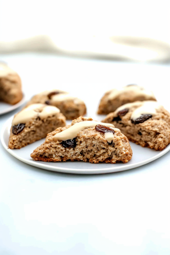 Freshly baked scones arranged to showcase visible oats, raisins, and shiny glaze.