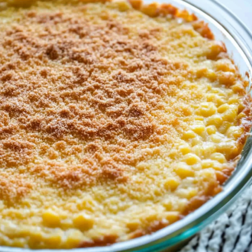 Final presentation of baked corn pudding, resting on a cloth with its golden surface catching the light.