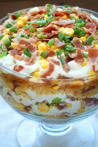 Savory cornbread salad in a clear bowl, topped with bacon and creamy dressing