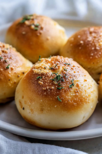 Plate of freshly baked bread bombs, highlighting the shiny crust and sprinkled toppings.