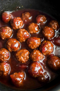 Overhead shot of meatballs in thick sauce, fresh herbs adding contrast to the dish.