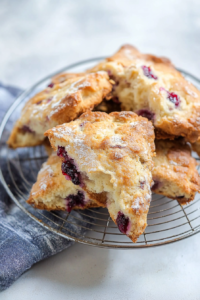 Golden-brown triangular scones cooling on a wire rack, dusted lightly with powdered sugar.