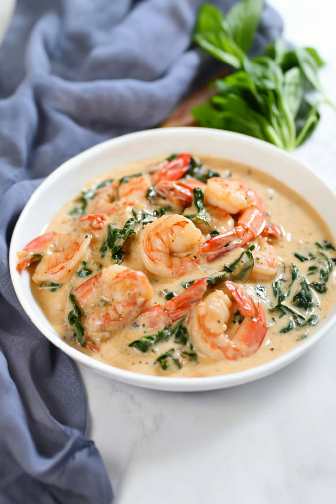 Comforting shrimp entrรฉe showcasing golden tones of sauce and bright green accents.