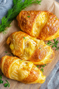 Three freshly baked pastries with glossy crust, garnished with sprigs of parsley.