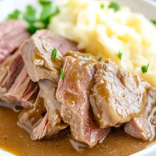 Final dish presentation of slow-cooked beef in savory gravy paired with buttery mashed potatoes.