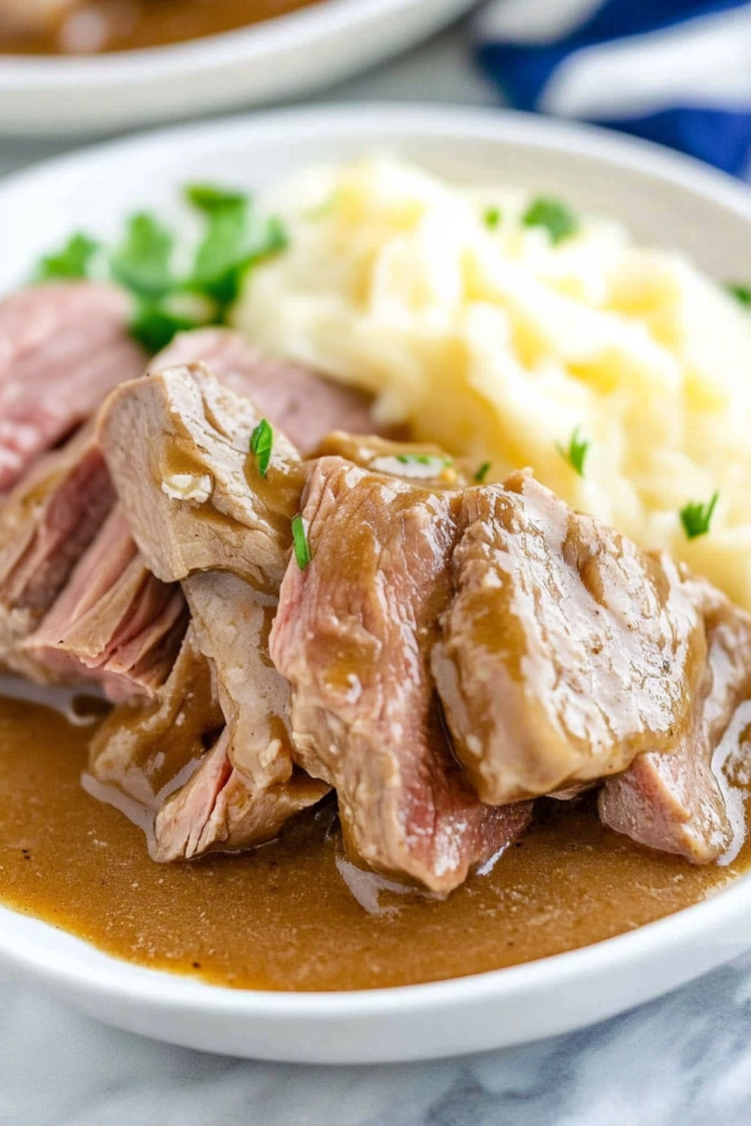 Final dish presentation of slow-cooked beef in savory gravy paired with buttery mashed potatoes.